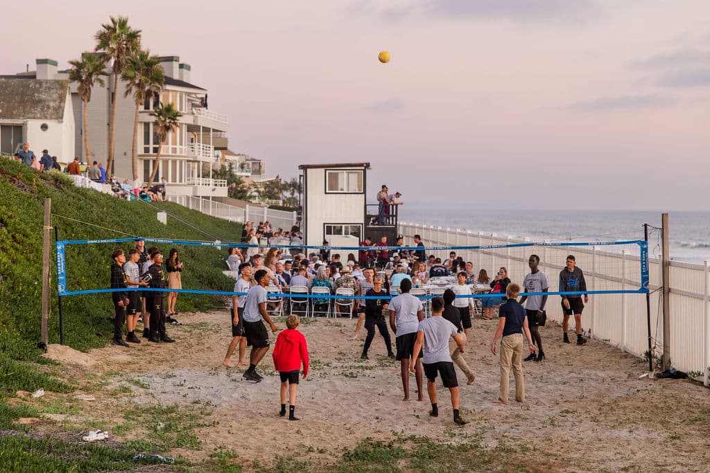 students engaged in a volleyball game on a sunny beach