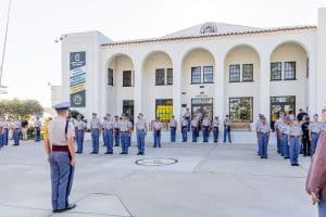 A group of disciplined cadets in uniform stand in formation