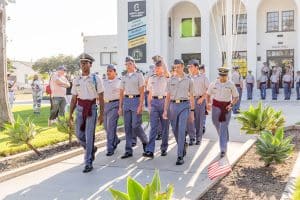 A group of cadets in uniform marches on a pathway
