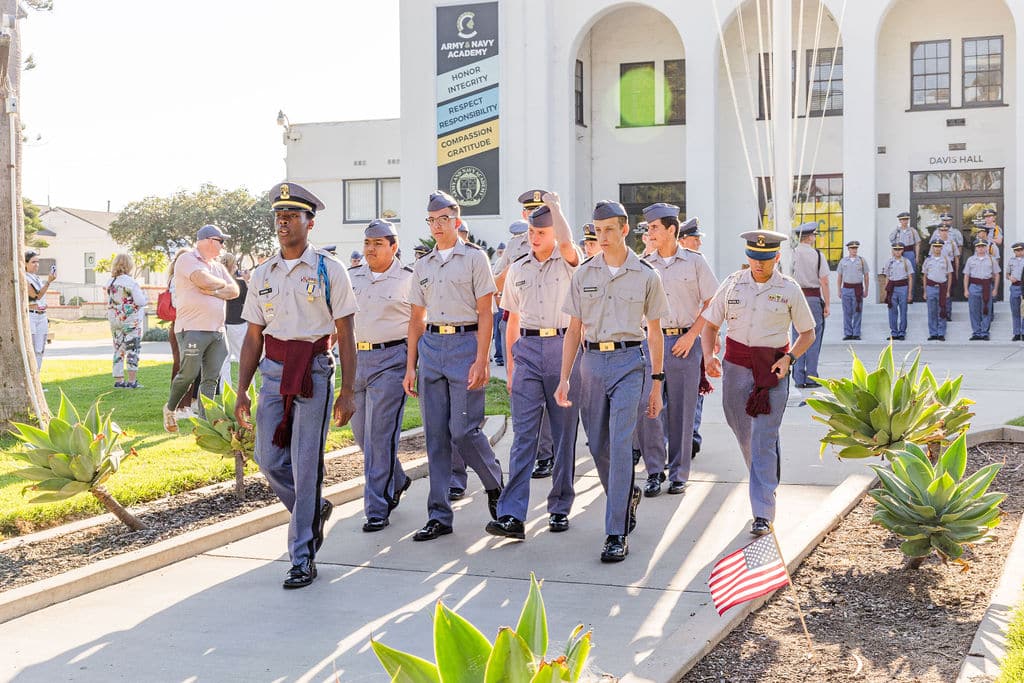 A group of cadets in uniform marches on a pathway